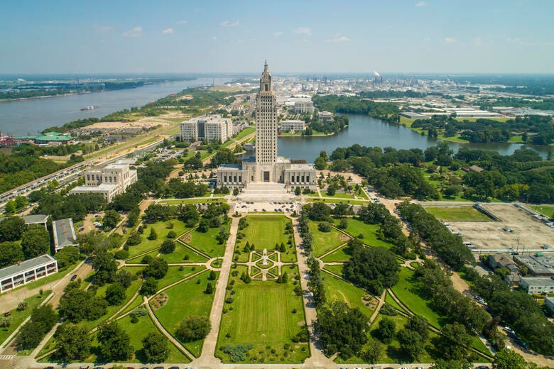 a large building with a tower surrounded by trees and a body of water