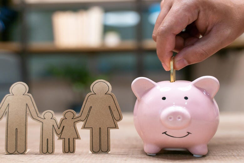 a hand holding a small pink piggy bank with a note