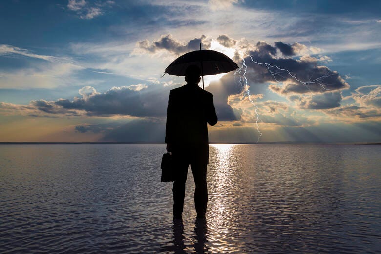 a person standing in the water holding an umbrella