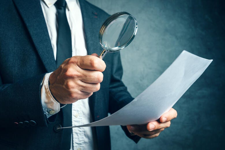 a man holding a magnifying glass and a paper