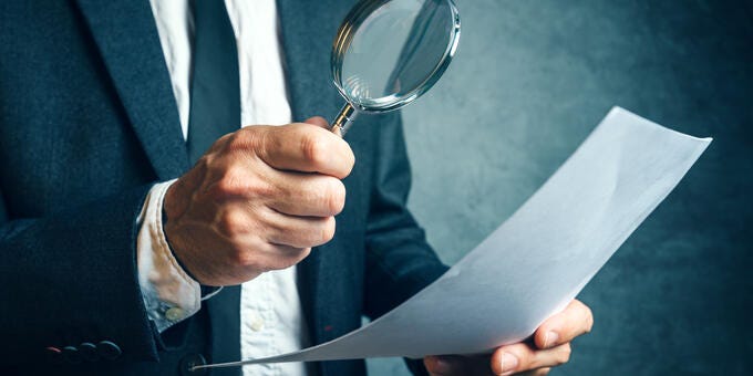 a man holding a magnifying glass and a paper