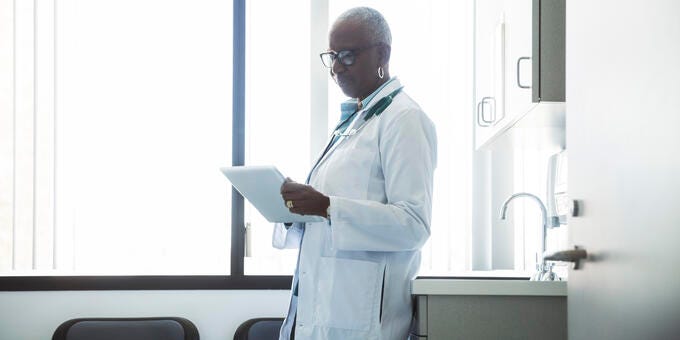 a man in a white coat holding a tablet