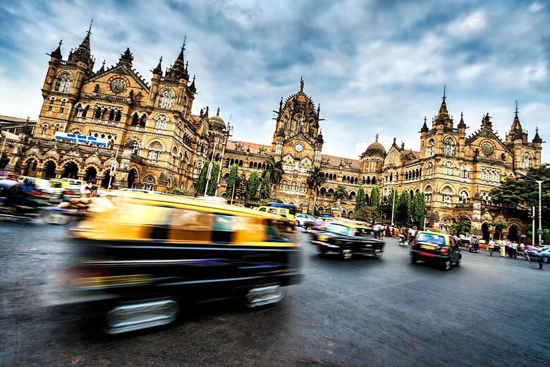 a busy street in front of a large building with Chhatrapati Shivaji Terminus in the background