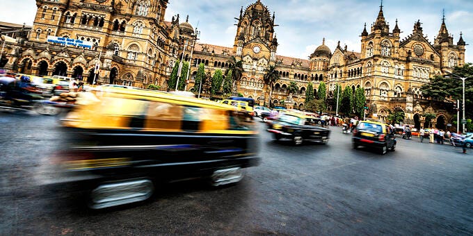 a busy street in front of a large building with Chhatrapati Shivaji Terminus in the background