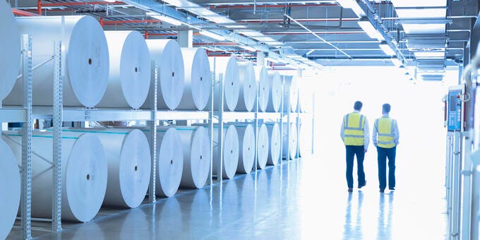 men in yellow vests standing in a room with white circular objects