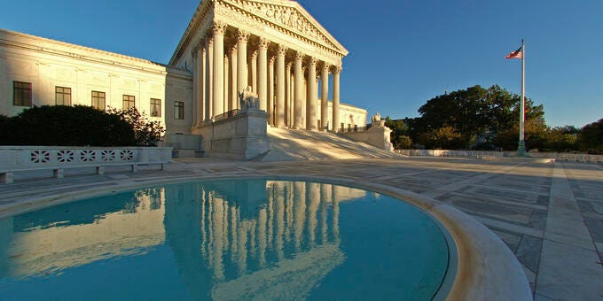 a large building with columns and a pool in front of it