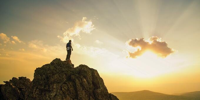 a person standing on a rock with Christ the Redeemer in the background